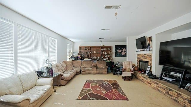 Spacious family room featuring sectional seating, carpet, a brick fireplace, and large windows with blinds